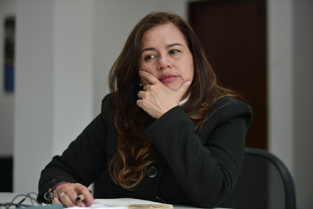 Imagen de una mujer con una sonrisa, bandera de la República de Colombia y foto del actual Presidente de la República de Colombi